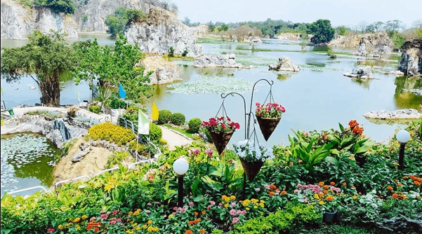 vườn hoa nhiều loài hoa khác nhau kế bên là hồ nước và những tảng đá lớn 