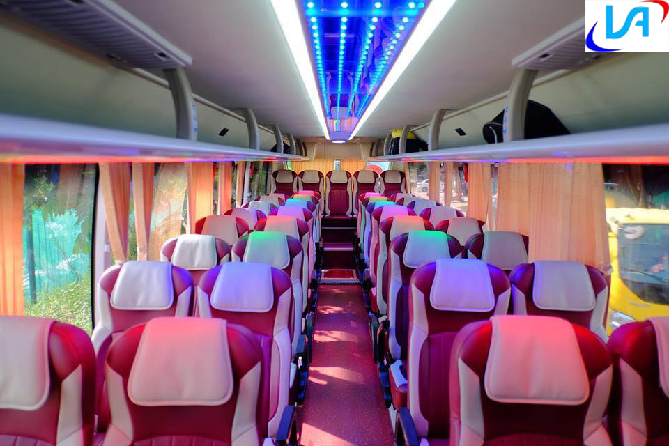 hai hàng ghế màu đỏ trắng phía trên có đèn màu xanh hai bên ghế là rèm cửa màu cam thuê xe du lịch Ninh Thuận