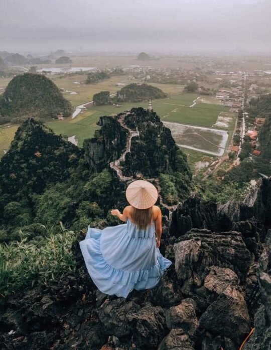 có một cô gái váy màu xanh đứng trên núi nhìn xa xăm tại THuê xe Ninh Bình
